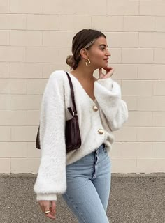 a woman is standing in front of a brick wall