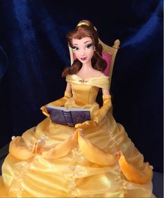 there is a cake that looks like a princess sitting in a chair reading a book