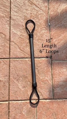 a large black scissors on a tile floor with measurements for length and width in front of it