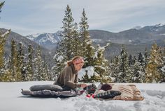 two people sitting in the snow eating food