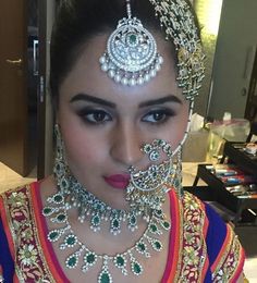 a woman in a bridal outfit with jewelry on her head and nosepieces