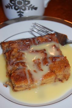 a piece of cake on a white plate with a fork and cup in the background