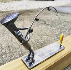 a metal sculpture of a fishing rod with a yellow fish on it's end