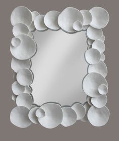 a mirror that is made out of white plates on the wall, with circles around it