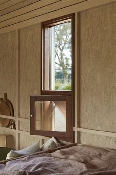 a bedroom with a bed and a window in the wall that is partially open to let light into the room