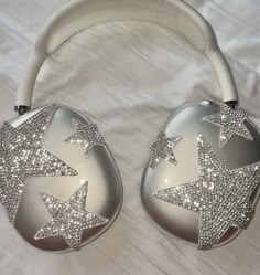 two silver and white christmas balls with stars on them, sitting on a white sheet