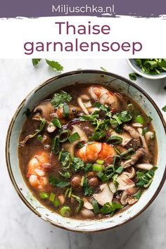 a bowl of soup with shrimp, mushrooms and greens on the table next to it