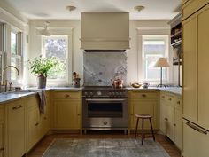 a kitchen with yellow cabinets and an oven in the center, along with a rug on the floor