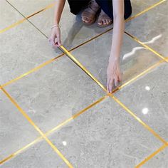 a woman kneeling down on the floor with her hands in the ground and yellow tape around her feet