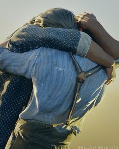 two people hugging each other in front of the sky