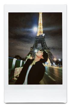 a woman standing in front of the eiffel tower at night with her eyes closed