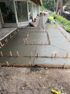 concrete being poured in front of a house with construction workers working on the side walk