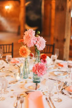 a wooden table topped with lots of plates and vases filled with flowers on top of it