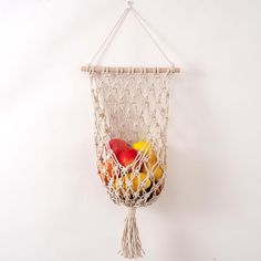 an apple, oranges and apples in a macrame bag hanging on a wall