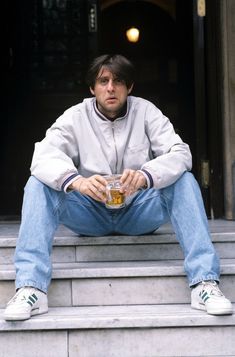 a man sitting on steps holding a drink