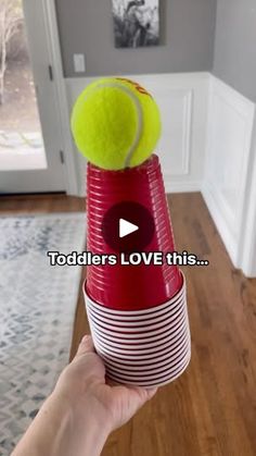 someone is holding up a plastic cup with a tennis ball on it and the words toddlers love this