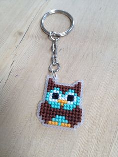 an owl keychain is shown on a wooden surface