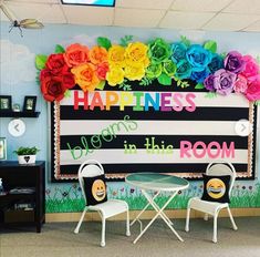 a classroom decorated with colorful paper flowers on the wall and chairs in front of it