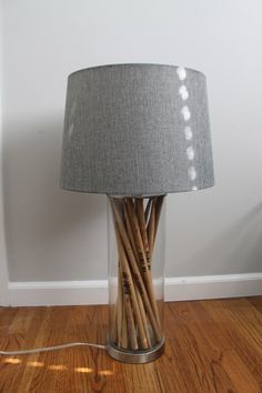 a lamp that is on top of a wooden floor in front of a white wall