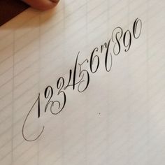 someone is writing on a piece of paper with cursive numbers in black ink