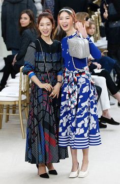 two young women standing next to each other in front of a room full of people