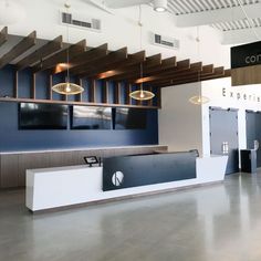 an empty lobby with blue walls and white counter tops, lights hanging from the ceiling