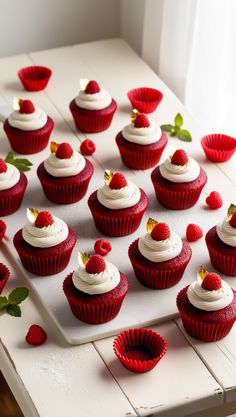 red velvet cupcakes with white frosting and topped with strawberries on a tray