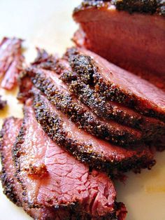 sliced meat sitting on top of a white plate next to some seasoning sprinkles