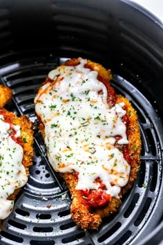 two pieces of chicken parmesan sitting on top of an air fryer