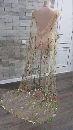 a mannequin with flowers and vines on it in front of a brick wall