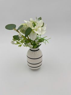 a white and black striped vase with flowers in it