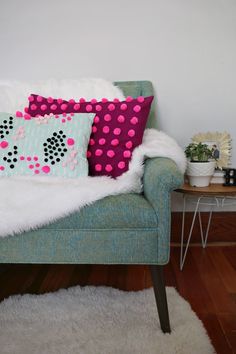 two pillows are sitting on a couch in front of a table with potted plants