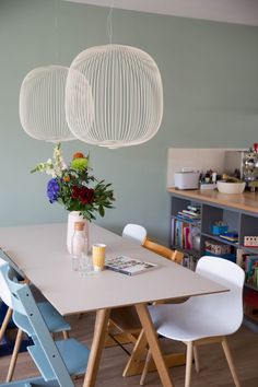 an image of a dining table with chairs and flowers on the table in front of it