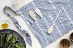 three wooden spoons sitting on top of a blue towel next to bowls and plates