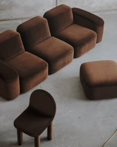 a group of brown couches sitting next to each other on top of a cement floor