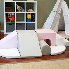 a play room with toys and bookshelves in the corner, including a teepee tent