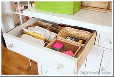 an organized drawer in a white cabinet filled with books and office supplies on top of a wooden floor