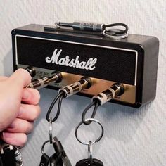 a person is holding two keys to a marshall amp wall mounted on a white wall