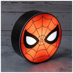 a light up spider man face on a wooden surface with white eyes and black rim