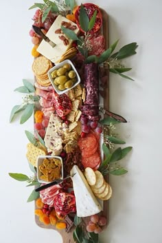 a wooden platter filled with different types of cheeses and crackers on top of each other