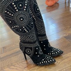 a pair of black high heeled boots with silver studs