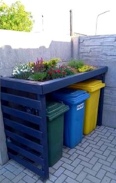 an outdoor planter with flowers and trash cans