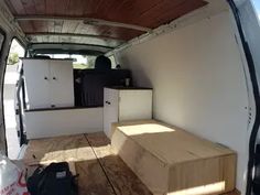 the interior of an empty van with wood flooring and storage boxes in the back