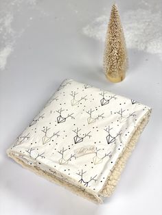 a white blanket sitting next to a small christmas tree