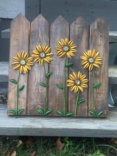 painted sunflowers are on the side of a wooden fence