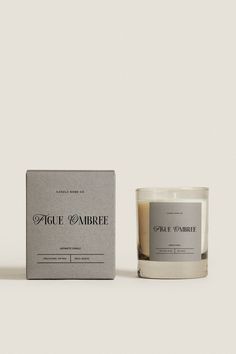 a candle sitting next to a box on a white surface with the words fige d'abre written in it