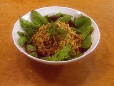 a white bowl filled with green vegetables on top of a wooden table