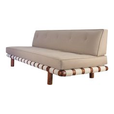 a beige and white striped couch sitting on top of a wooden frame