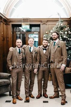 three men in suits and ties standing next to each other near a christmas tree at the hotel