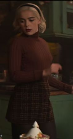 a woman standing in front of a cake on top of a table next to a plate